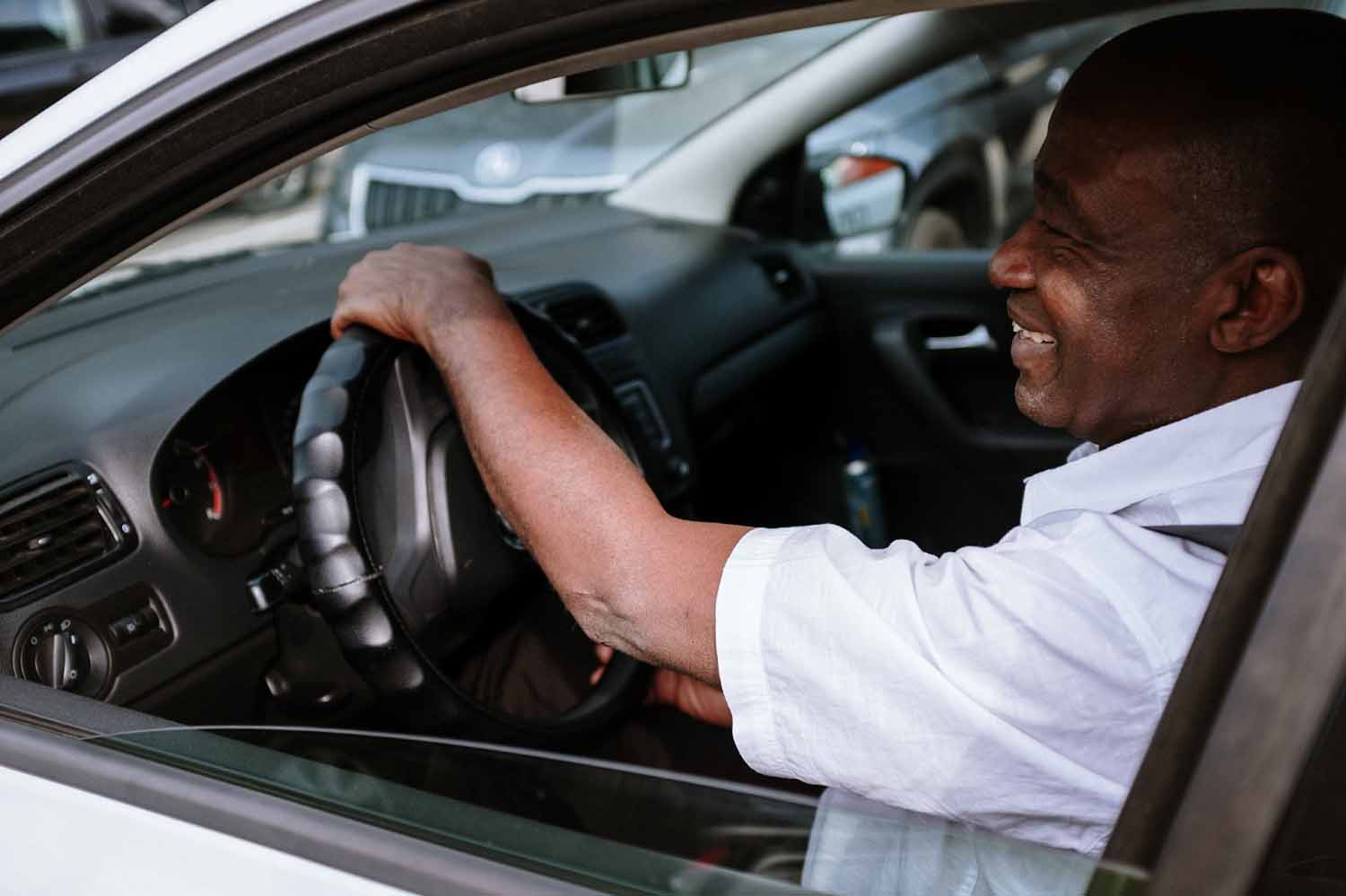 Older Man in driver seat of vehicle with seat belt buckled, smiling and practicing safe driving habits.