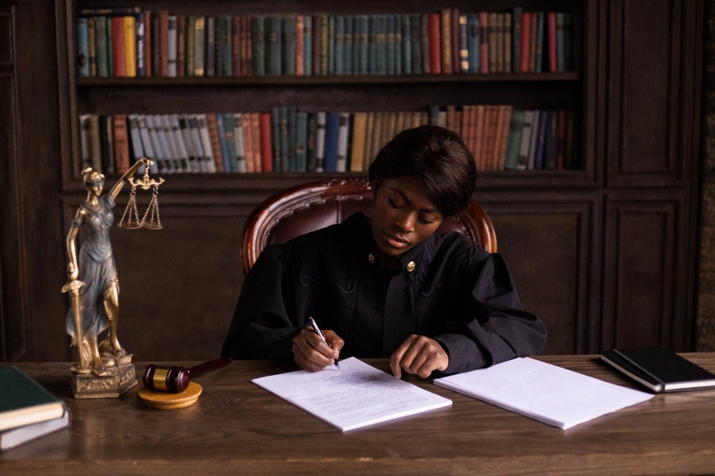 Young female judge at her desk with case paperwork, gavel, and scales