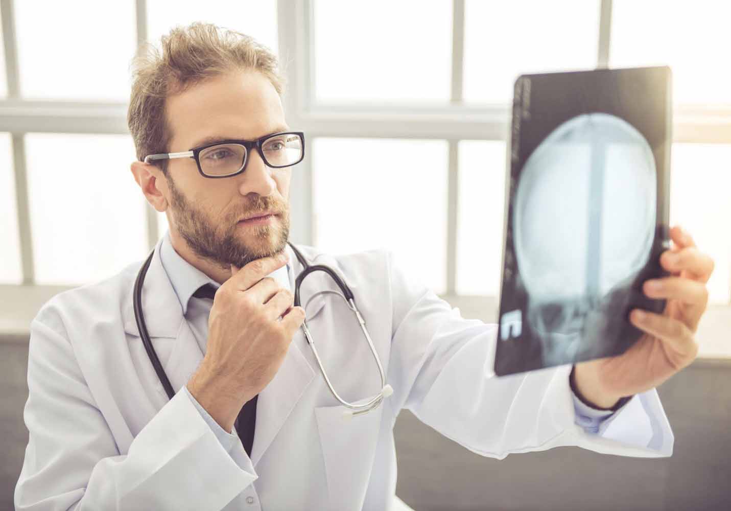 Doctor holds up an x-ray of a patient’s skull, looking for a TBI