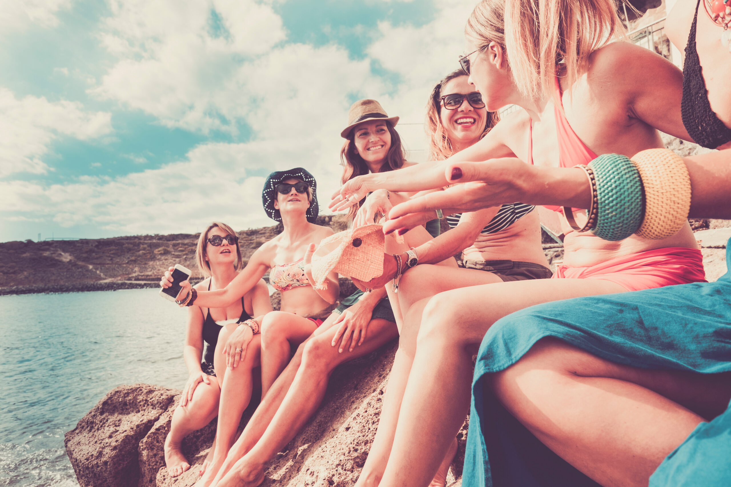 Large group of friends sitting on a rocky beach enjoying their safe spring break