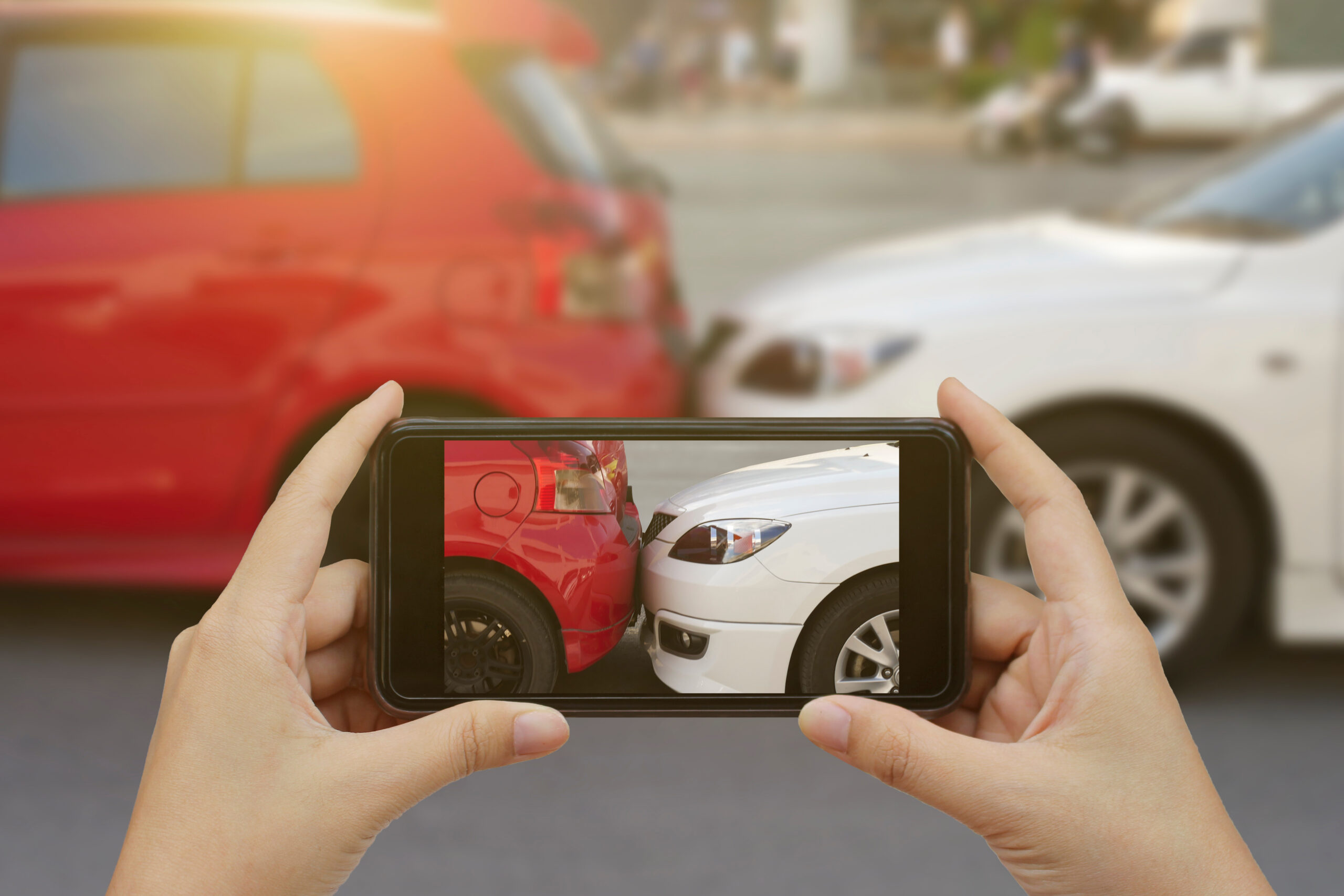 Close up of hands holding smartphone and taking a photo at the scene of a car crash accident