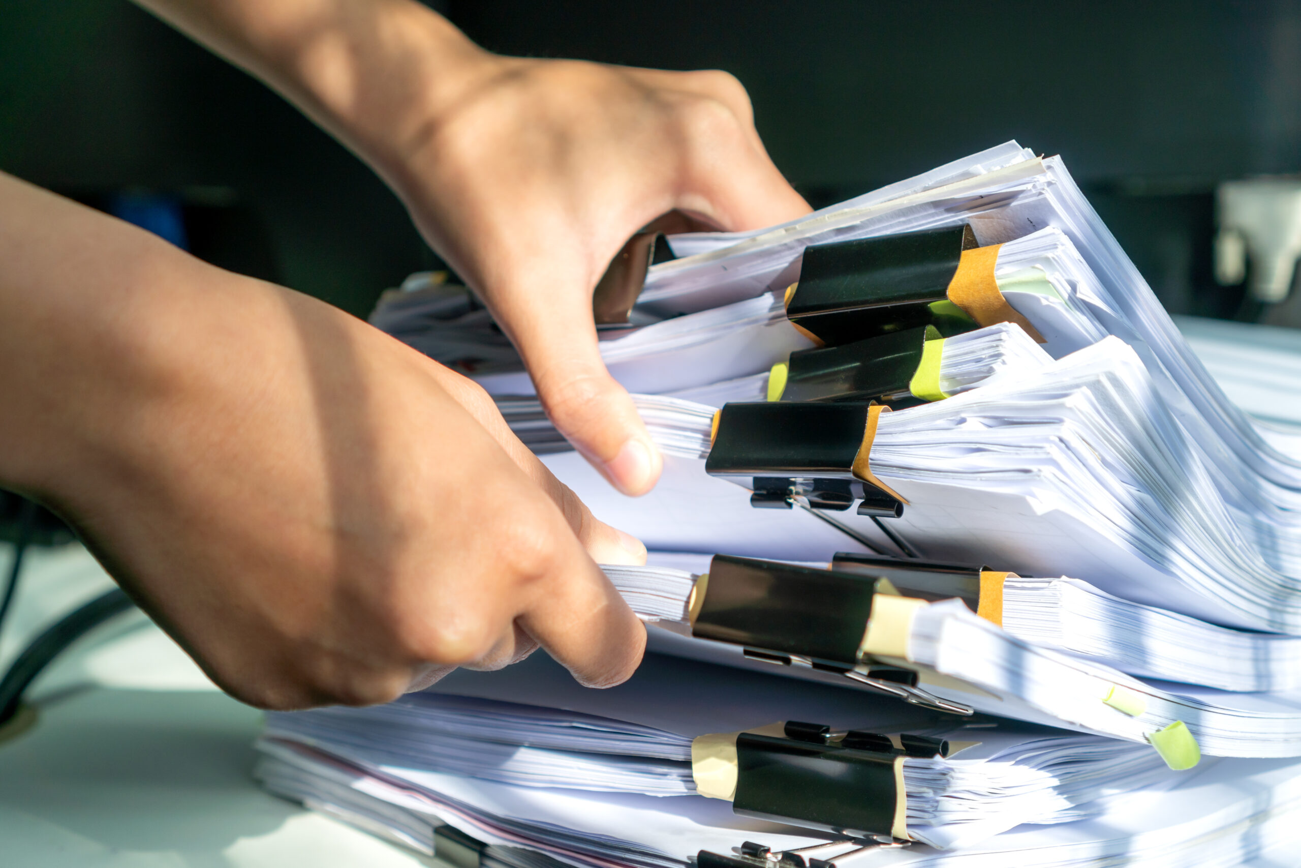 Woman holding stacks of paper evidence and reports organized with color-coding and binder clips