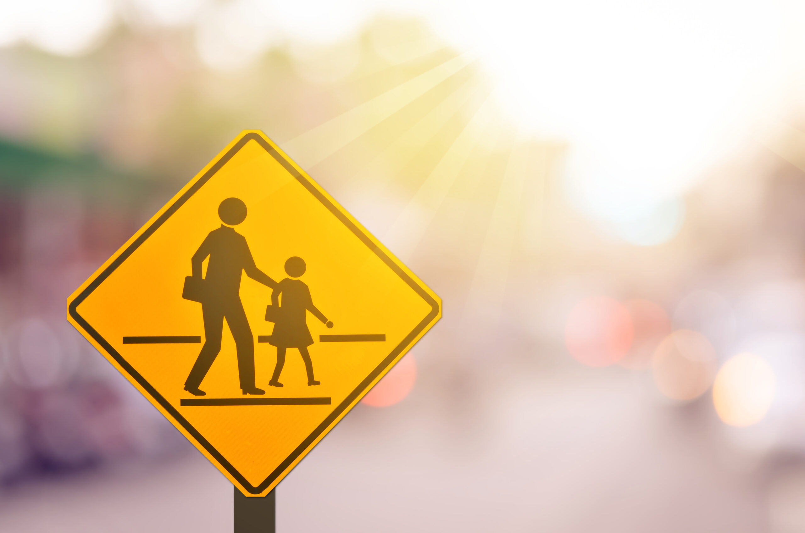 School zone warning sign on blur traffic road with colorful light abstract background