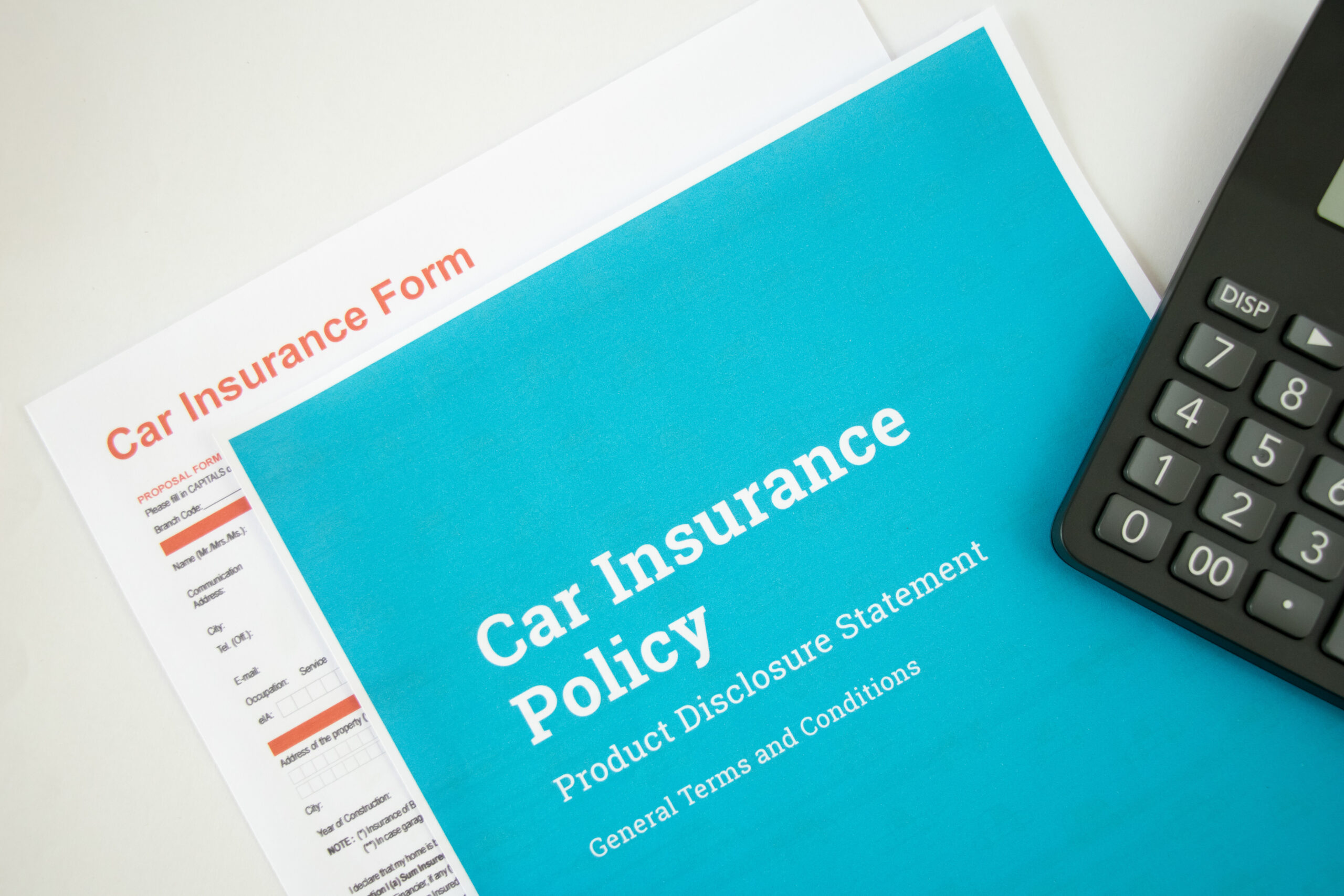 Top view of car insurance policy form and calculator on a white background