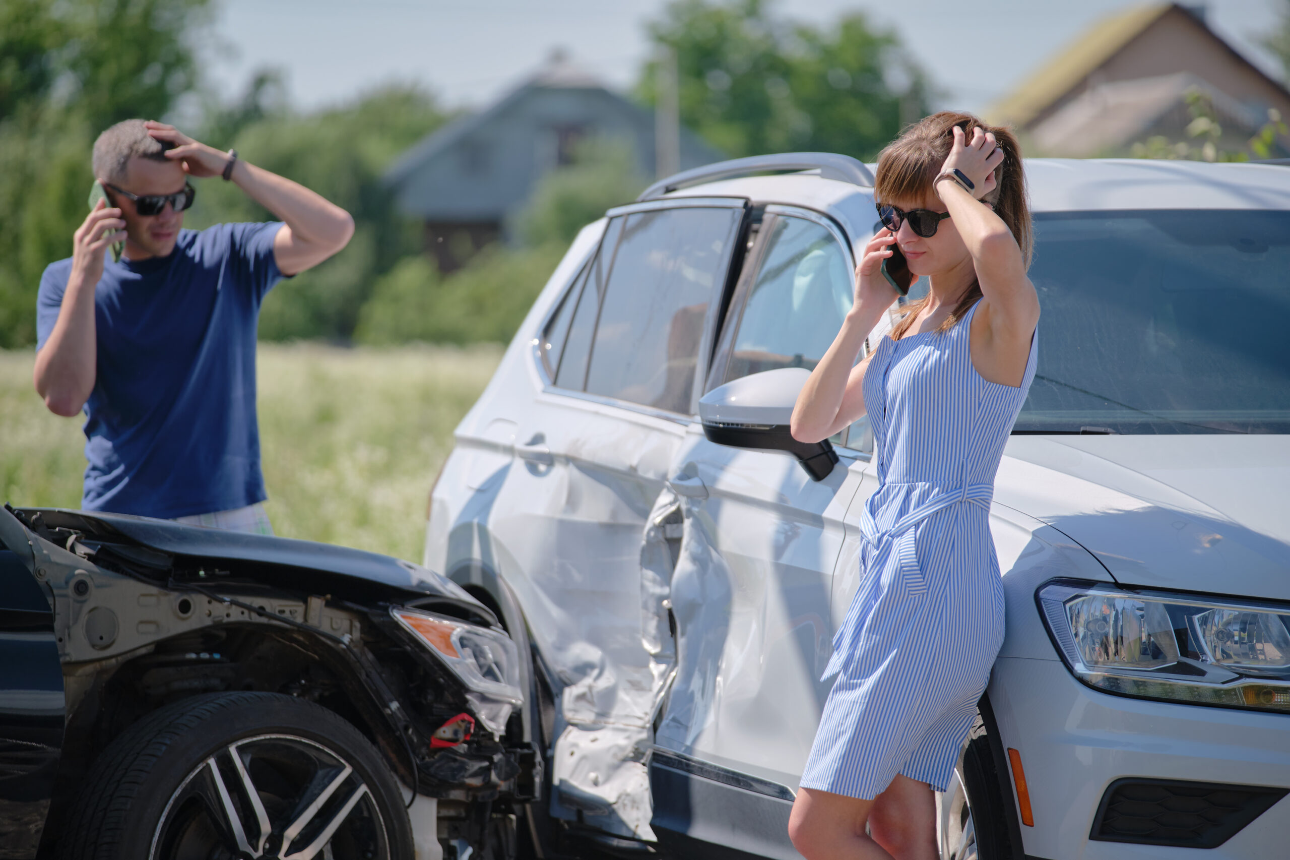 Angry woman and man drivers of heavily damaged vehicles calling insurance companies for help in car accident.