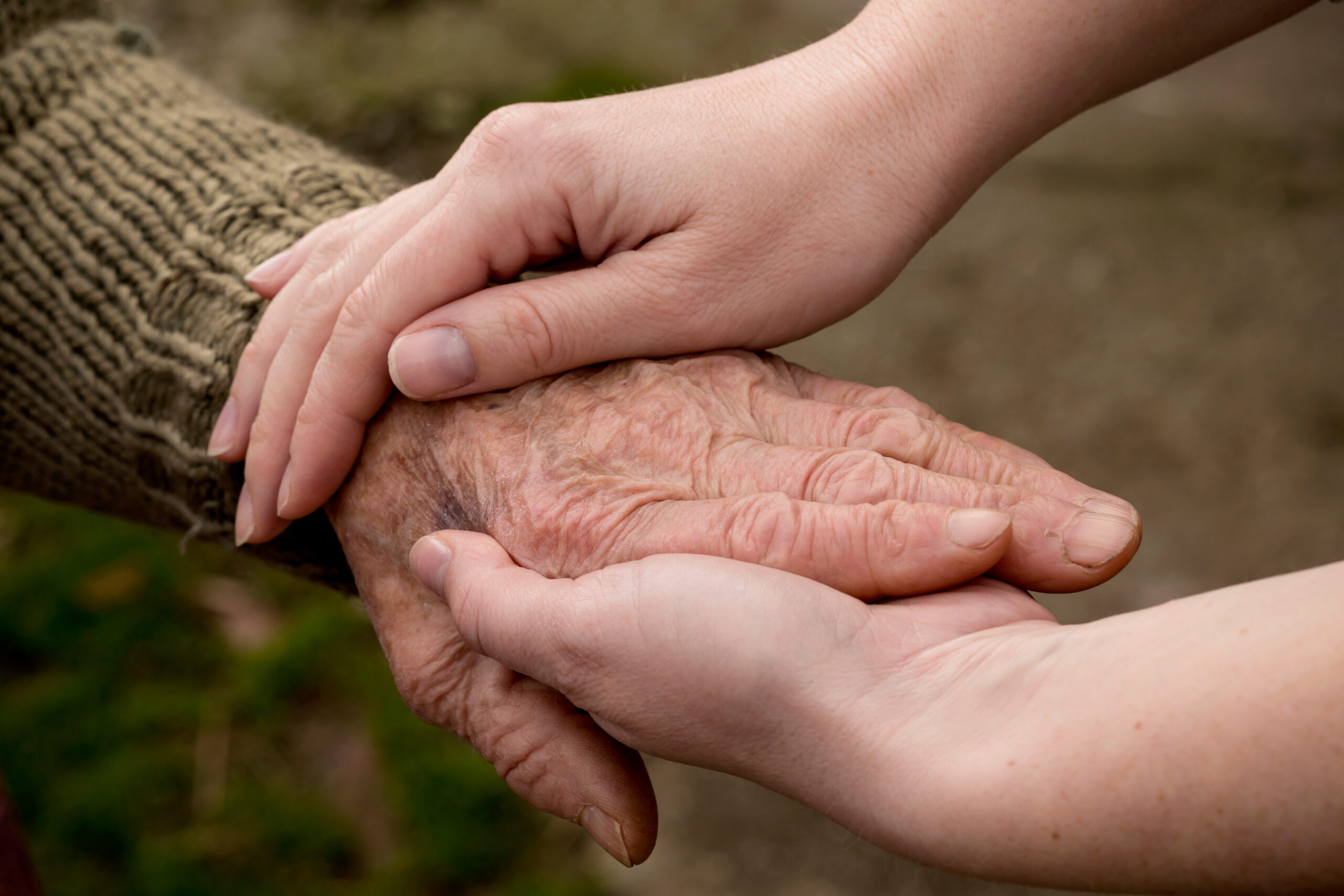 Young hands cradling an elderly hand