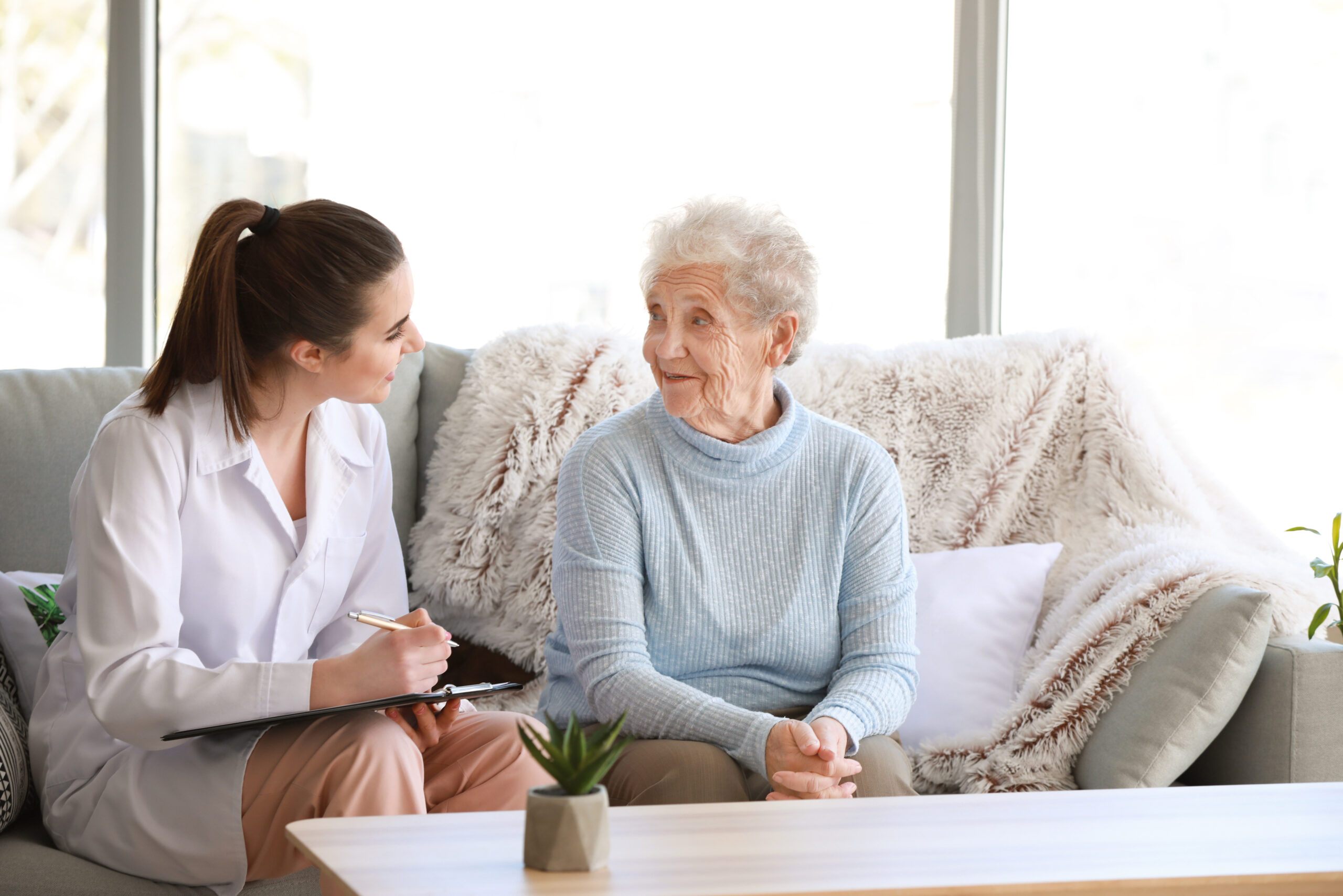 Female doctor sitting on a couch with her female Centenarian patient
