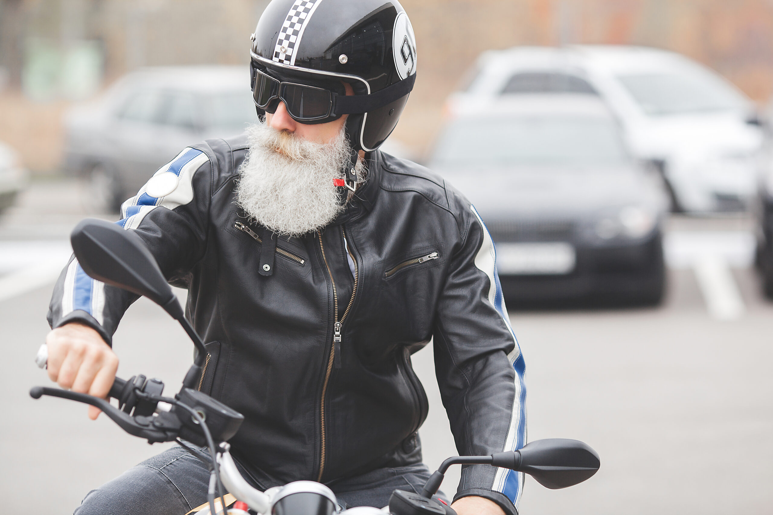 Older male on a motorcycle wearing a helmet and goggles