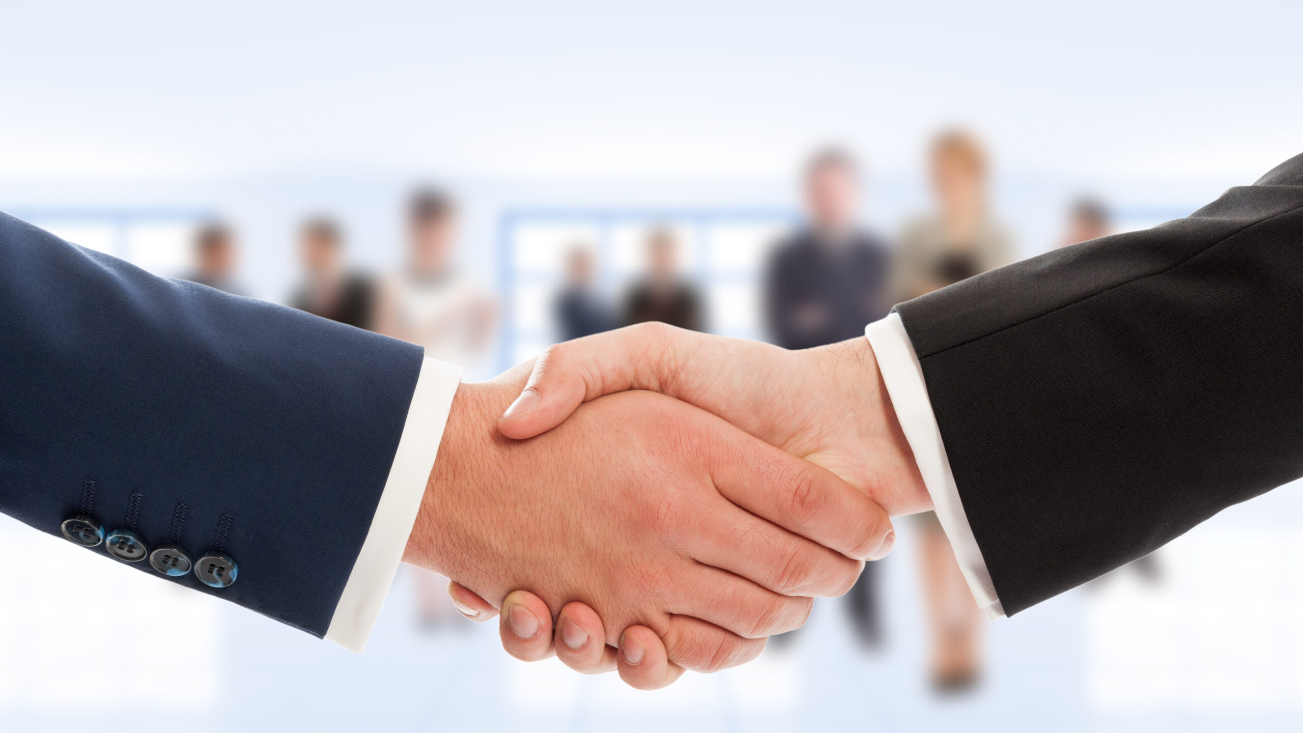 Businessmen shake hands with blurred business people in background