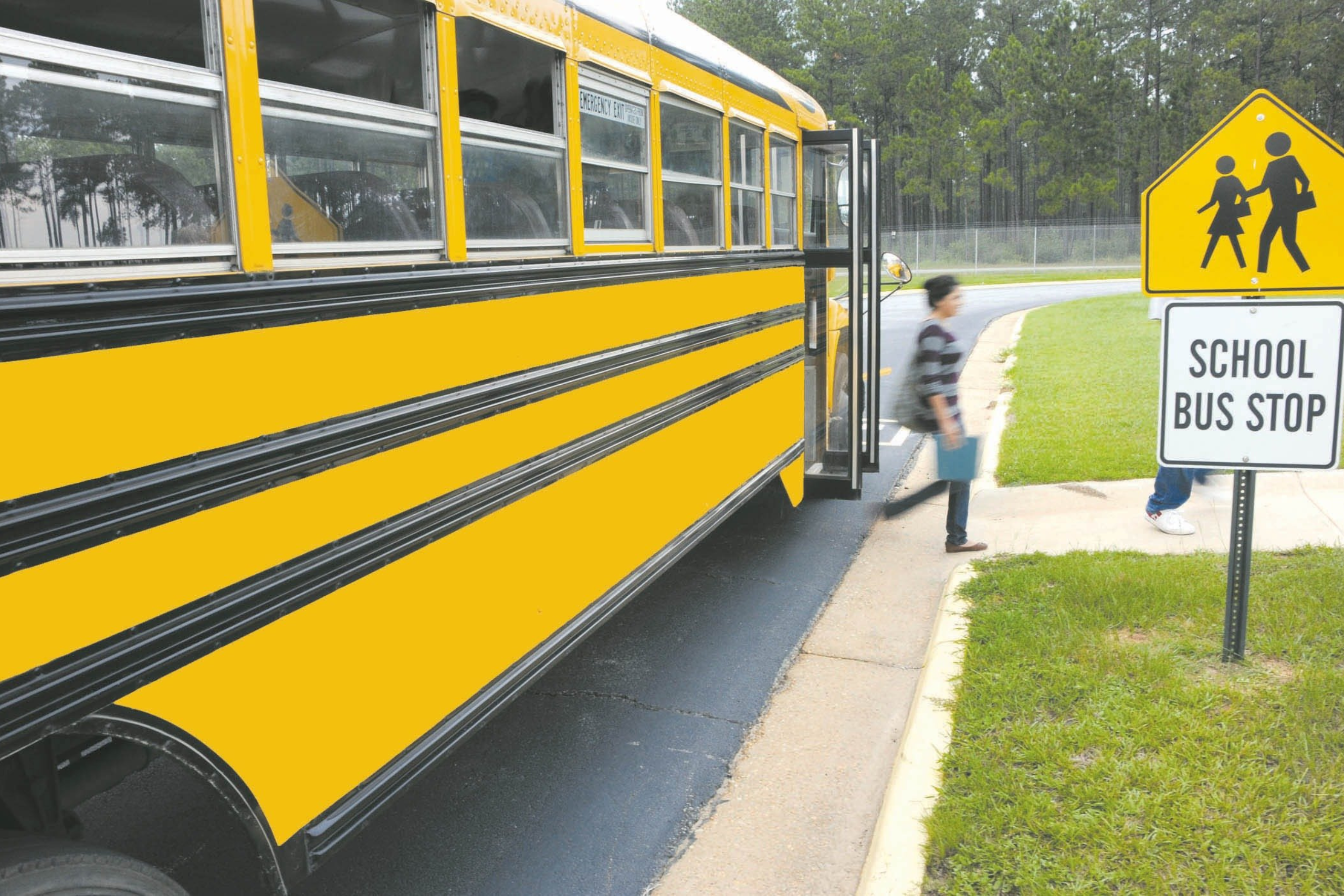 A student stepping off a school bus at a designated bus stop, highlighting the importance of pedestrian safety during National Traffic Awareness Month.