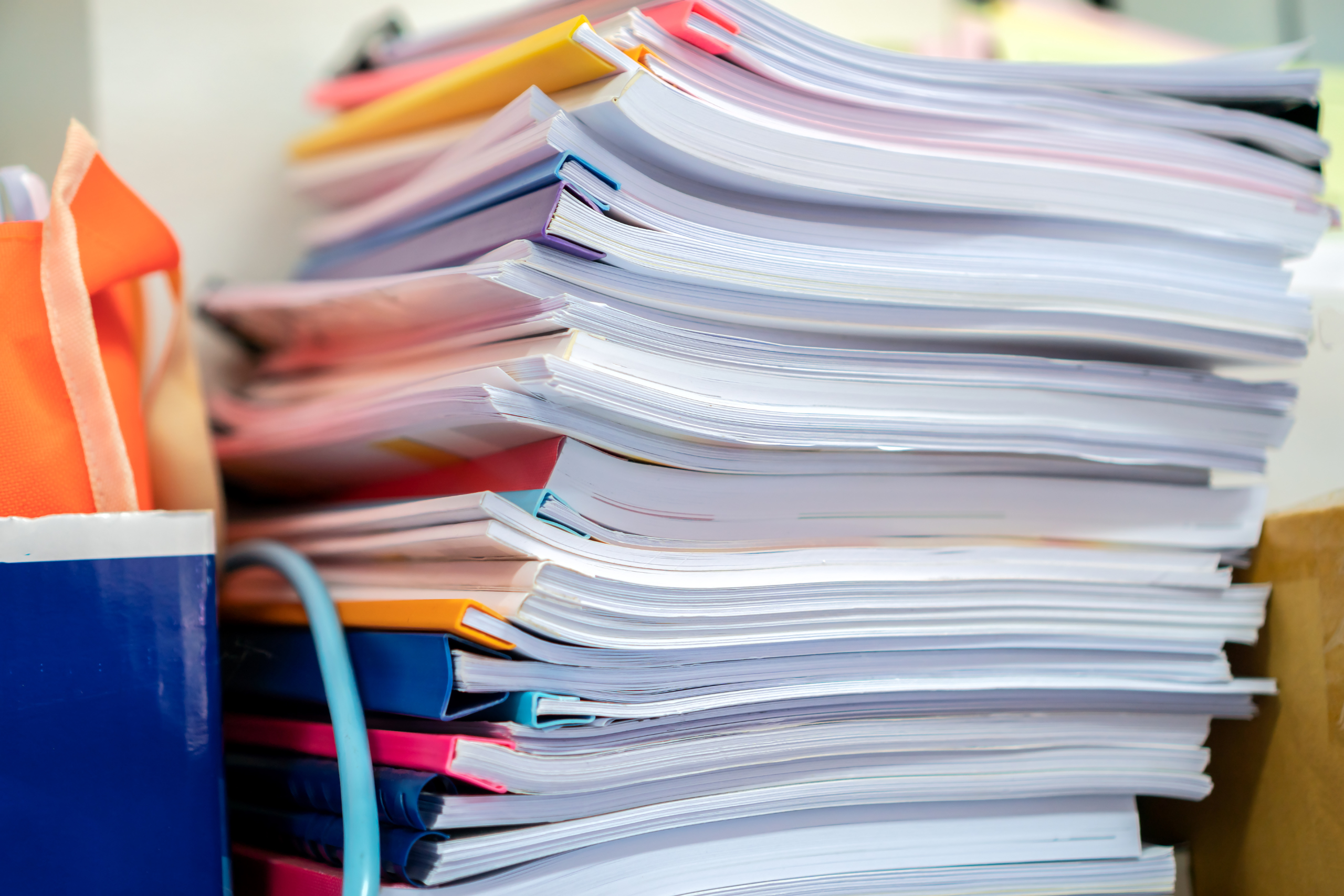 Stacks of assorted paperwork and files, indicating a busy office or administrative work.