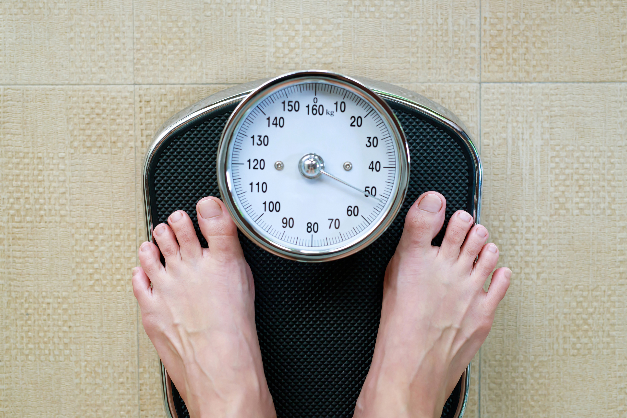 Close-up view of bare feet on a mechanical bathroom scale, illustrating weight monitoring or a health and wellness concept.