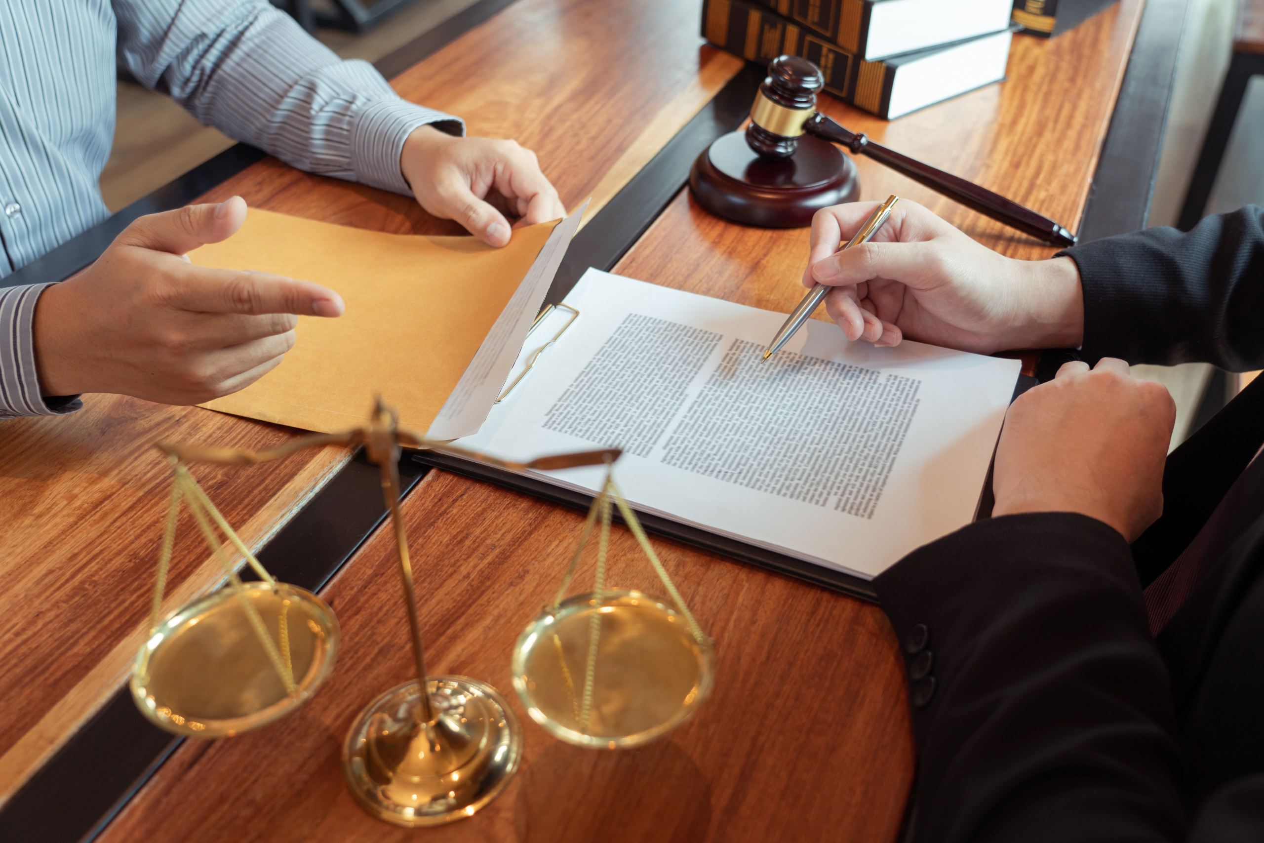 Two people reviewing nursing home legal documents at a desk with a gavel and scales of justice nearby.