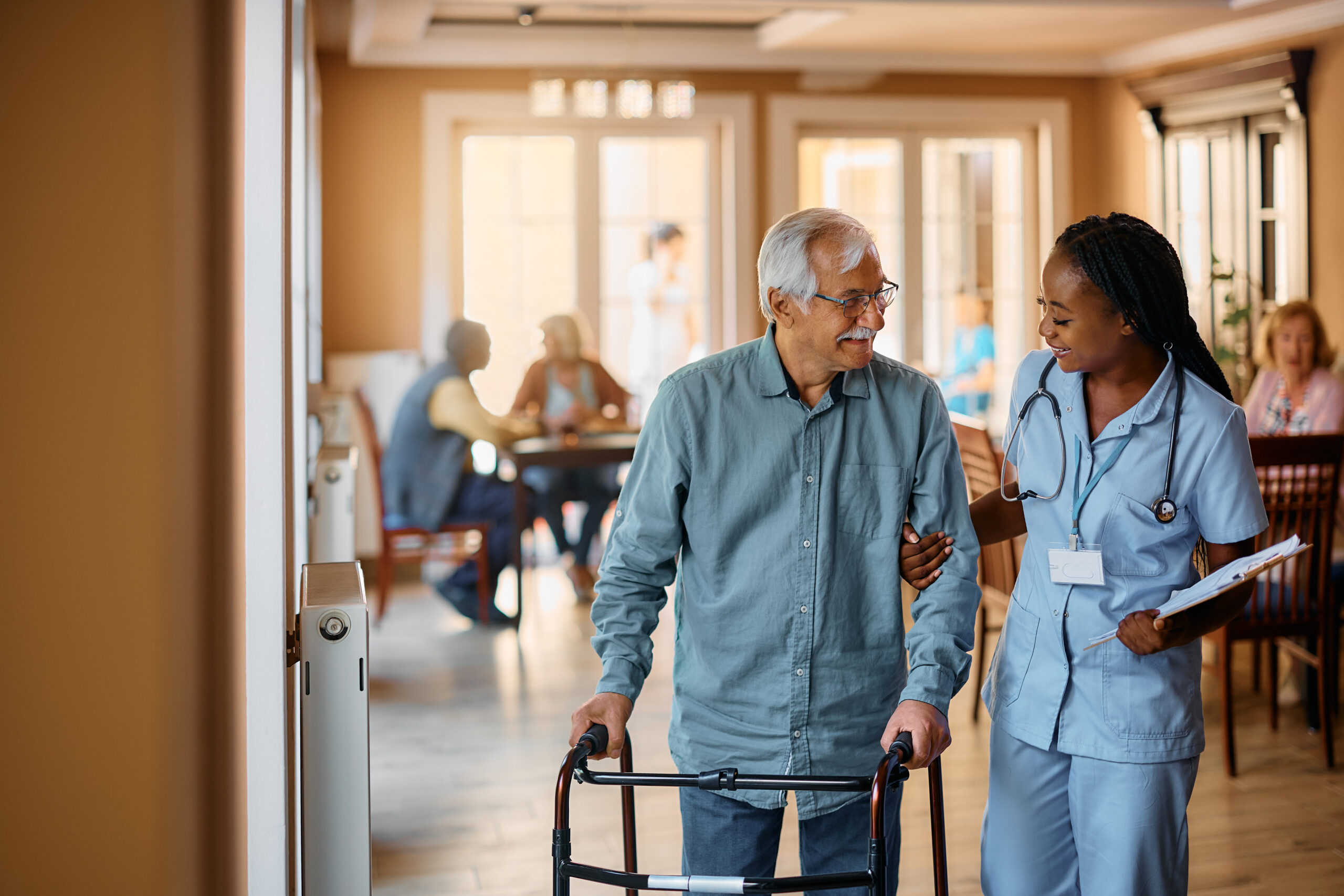 Nurse assisting an elderly man with a walker, emphasizing the importance of freedom of movement in nursing home care.