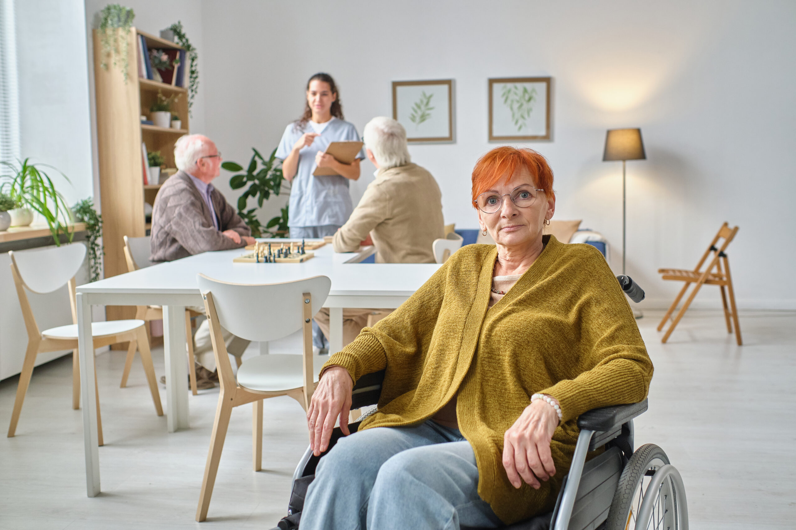 Elderly woman in a wheelchair with other seniors and a nurse in the background, representing the legal rights of nursing home residents.