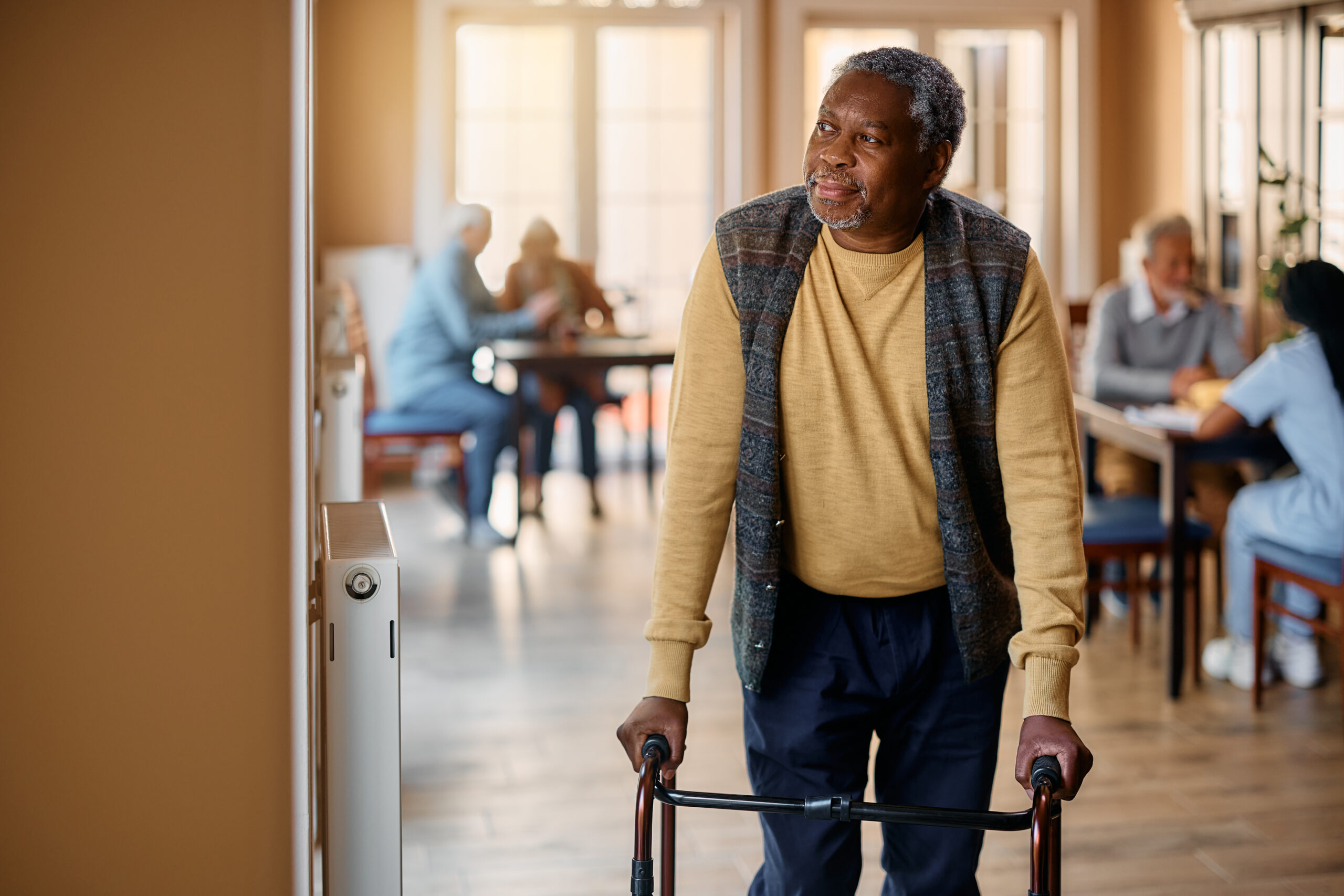 Elderly man using a walker in a nursing home, highlighting the vital role of mobility in nursing home care and rehabilitation.