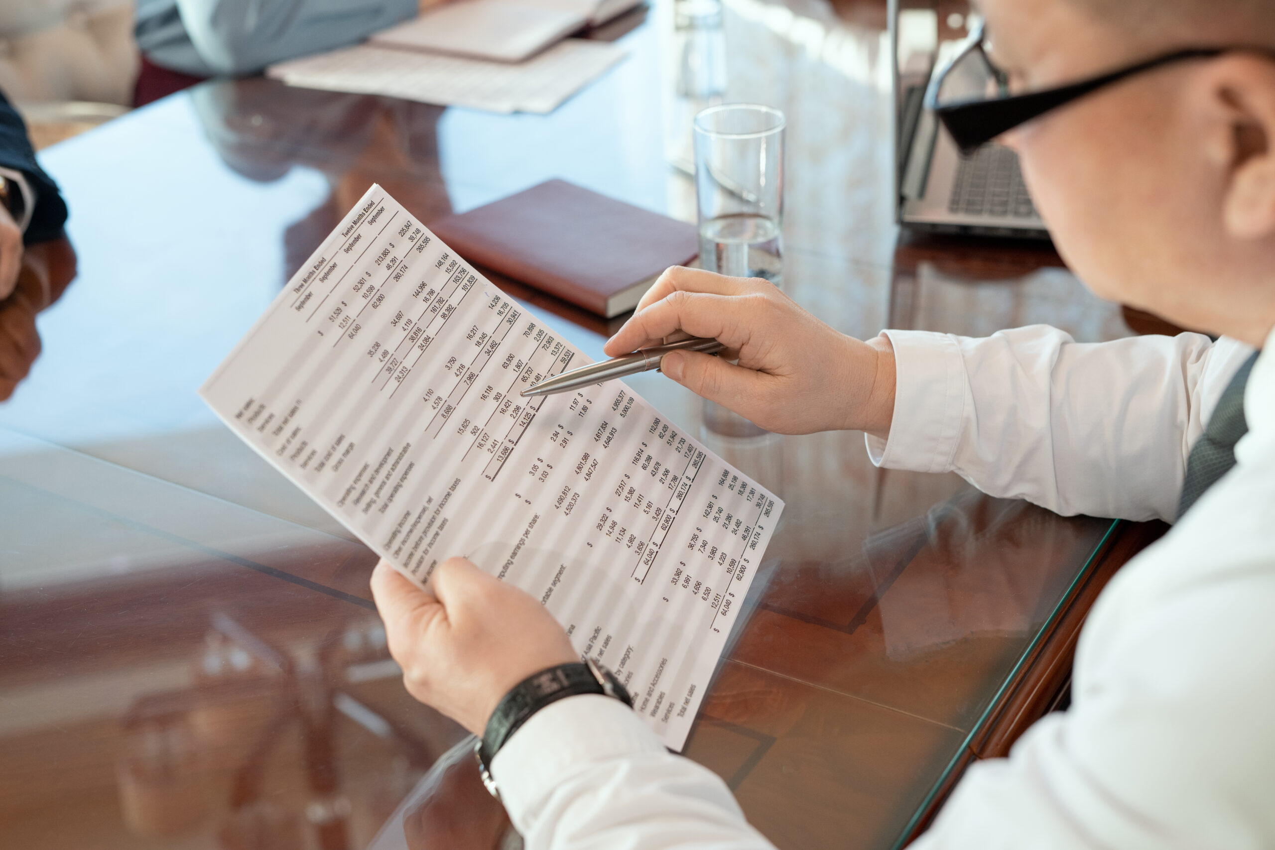 Person reviewing detailed documents with a pen at a desk, symbolizing legal or financial preparation after an accident.