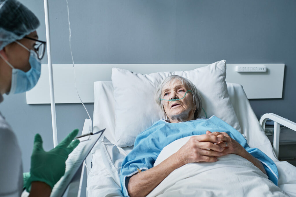 Elderly woman in hospital bed speaking with doctor, illustrating pressure ulcer risks and long-term care concerns. 