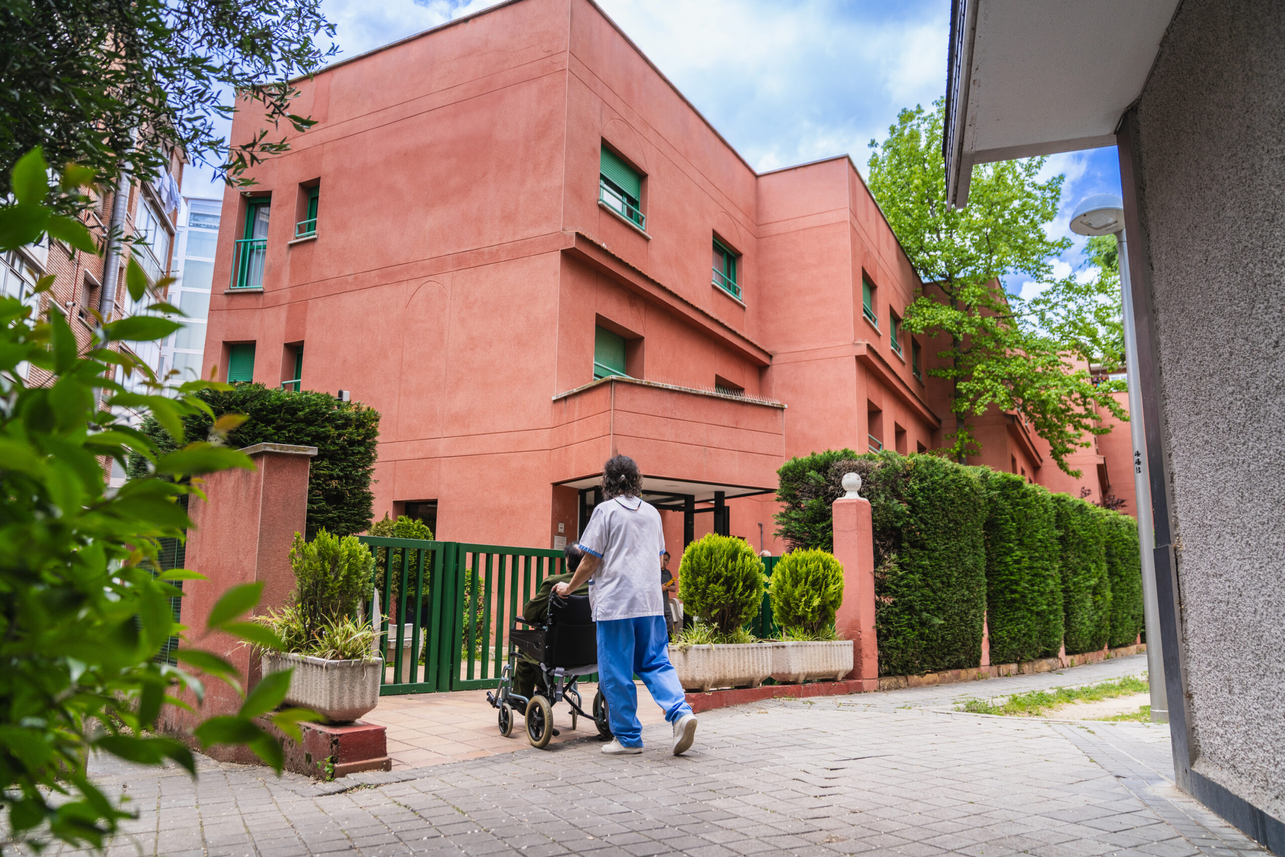 Caregiver pushing elderly resident in wheelchair outside nursing home; Williams DeLoatche handles nursing home abuse cases.