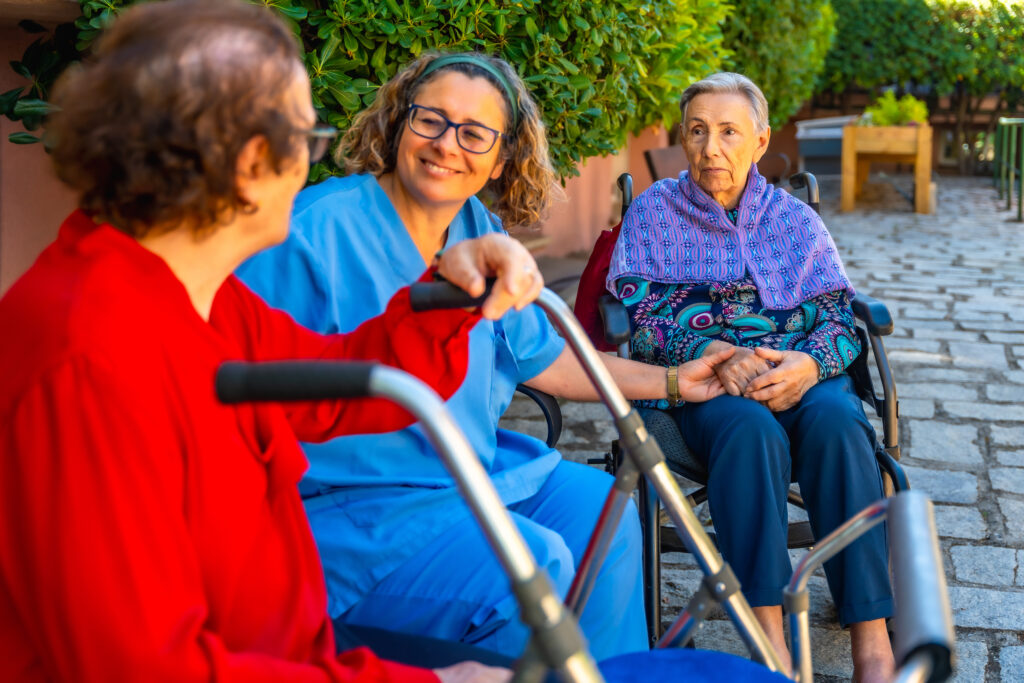 Nurse comforting elderly women outdoors at care facility; Williams DeLoatche supports nursing home abuse victims.