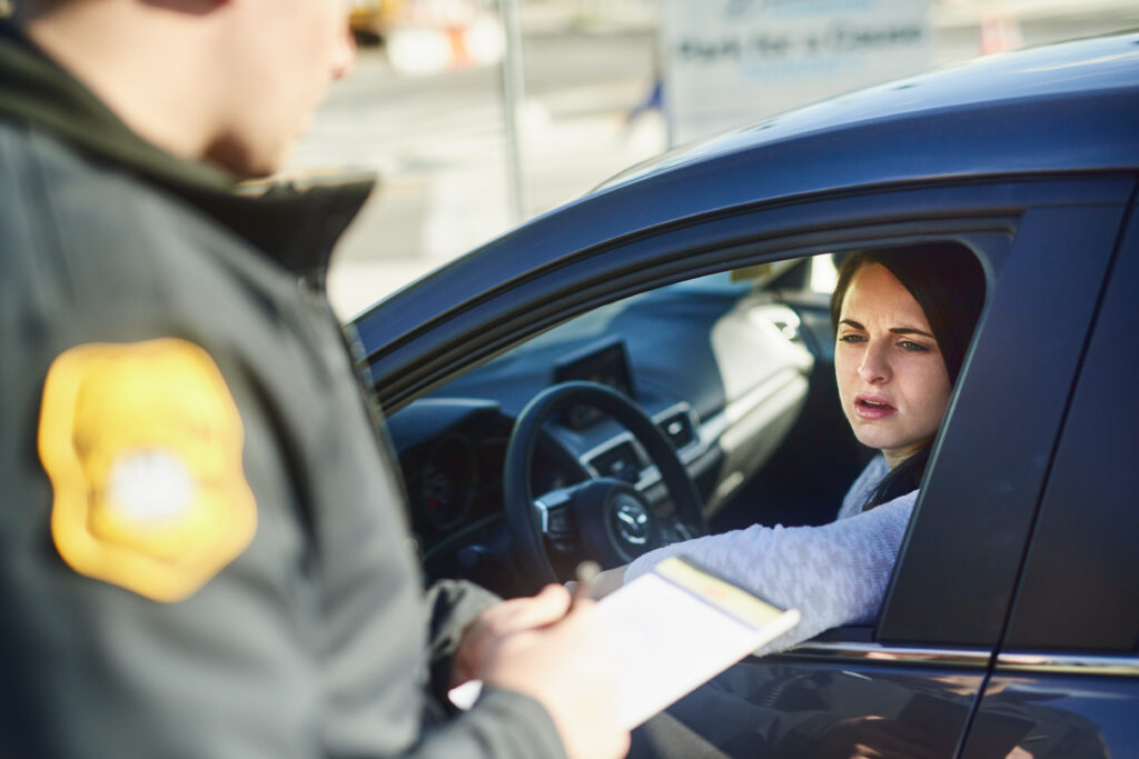 Police officer issuing citation to concerned female driver during a roadside traffic stop