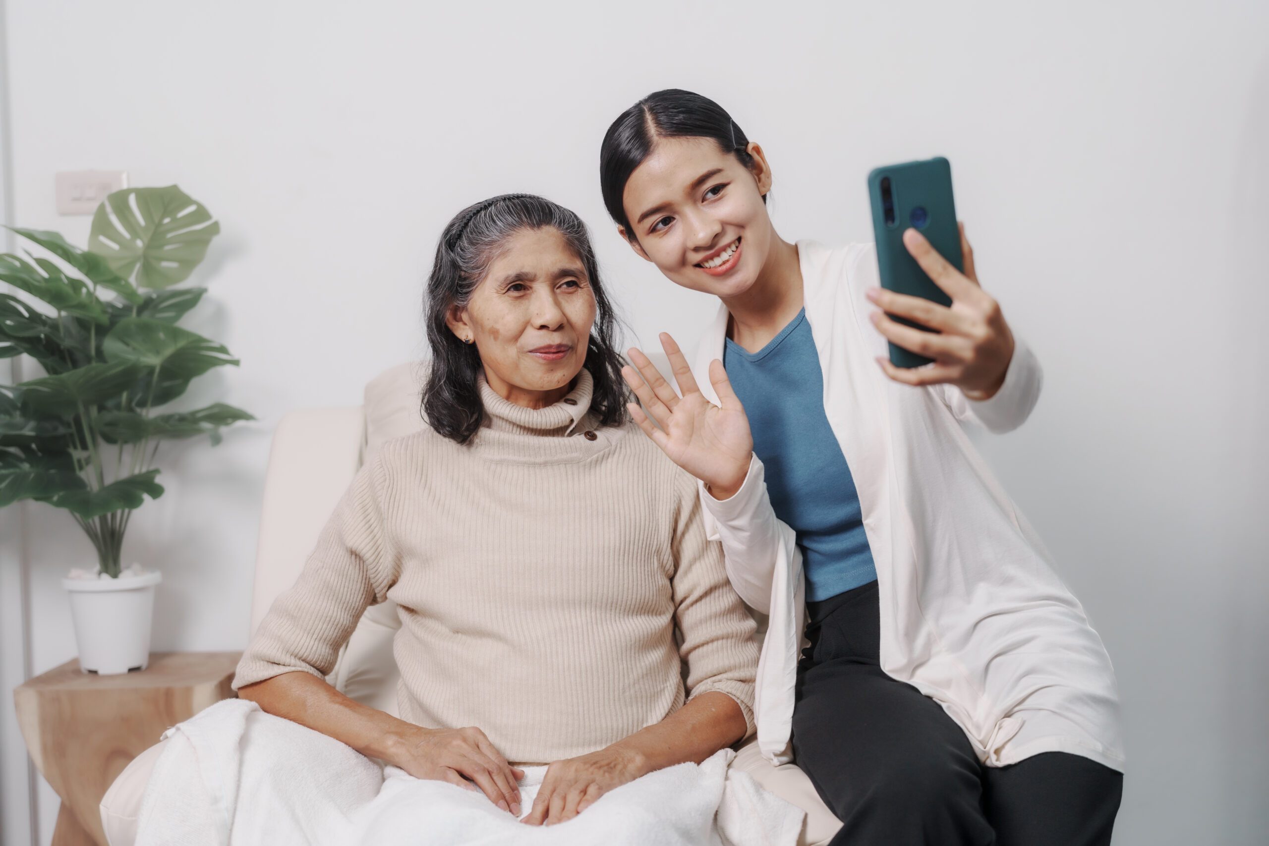 Young woman taking selfie with elderly relative, illustrating social media sharing during nursing home visits