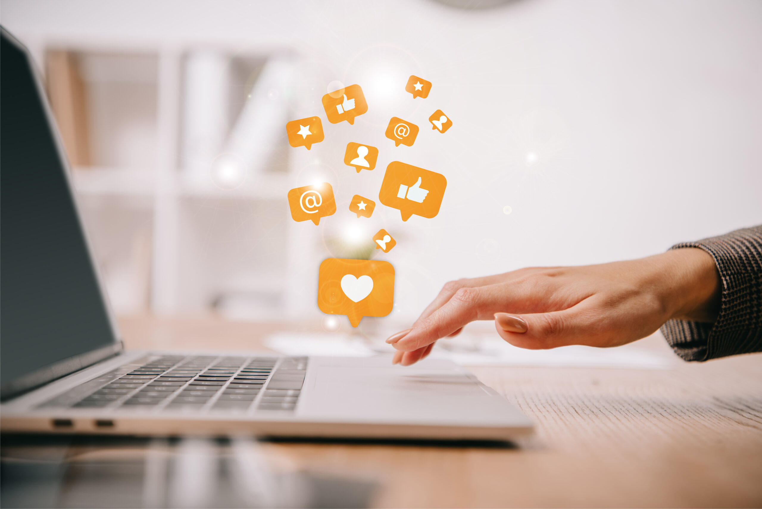 Hand using laptop with social media icons floating above, symbolizing online activity risks in legal cases