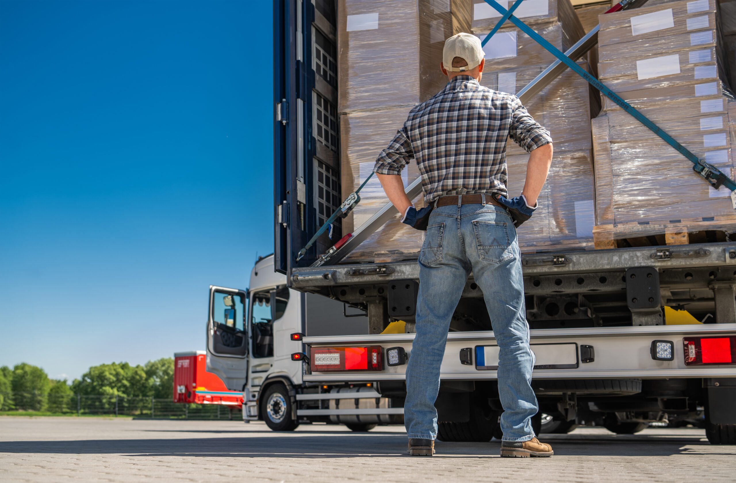 Truck driver inspecting unsecured cargo pallets, showing potential cause of a trucking accident