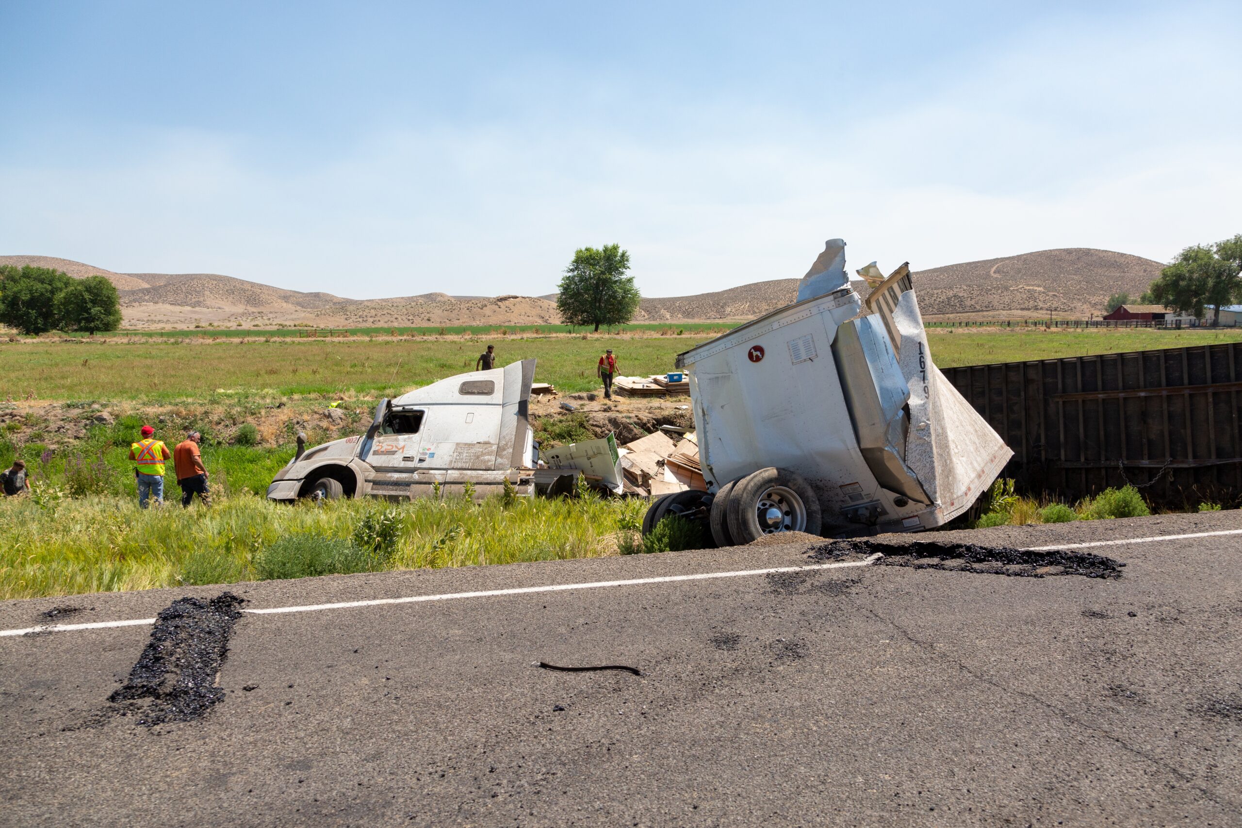 Overturned semi-truck and damaged trailer off rural highway, aftermath of a trucking accident