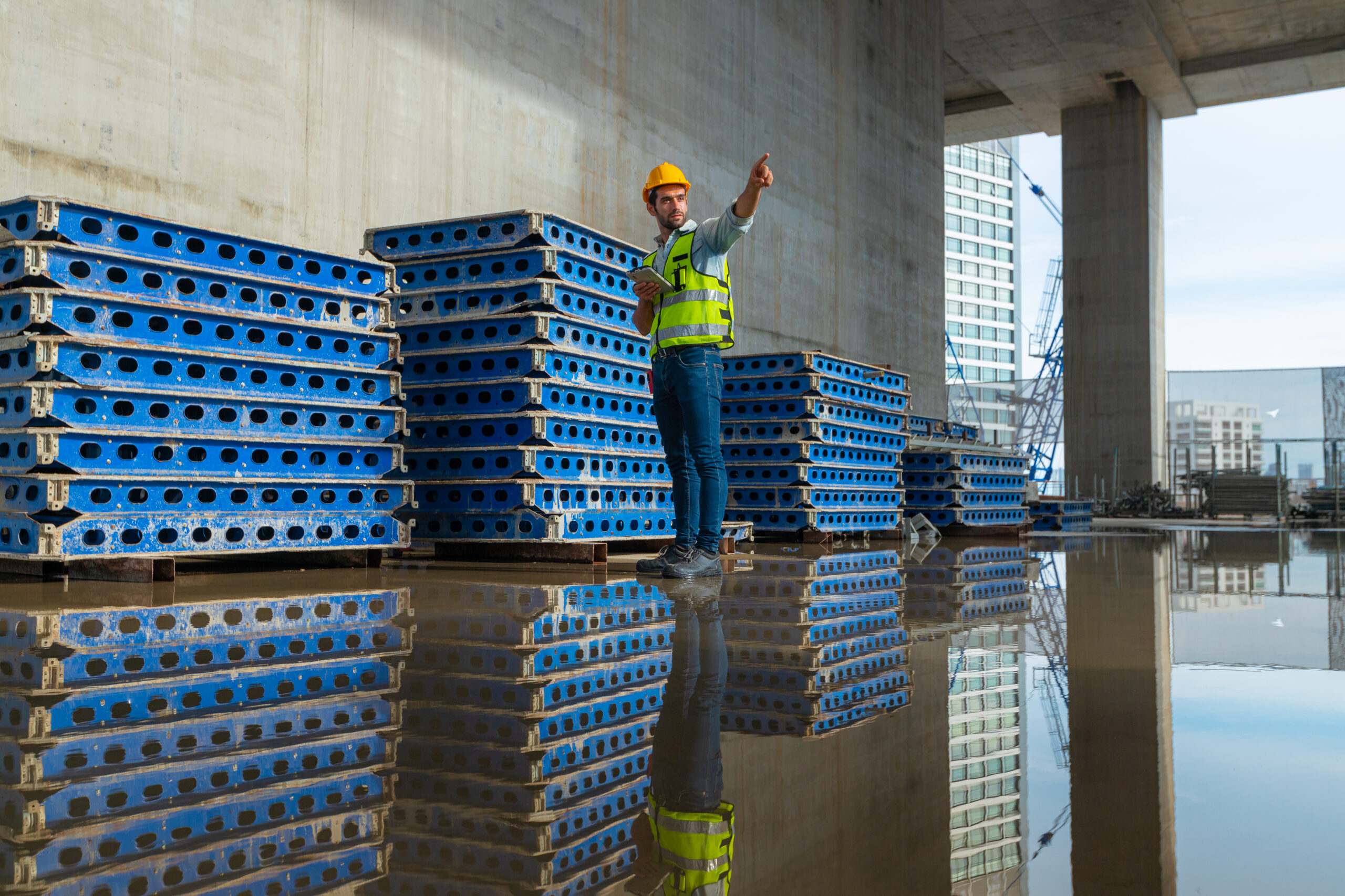 Construction worker pointing near water-covered floor; Williams DeLoatche stresses capturing unsafe site conditions for injury claims.