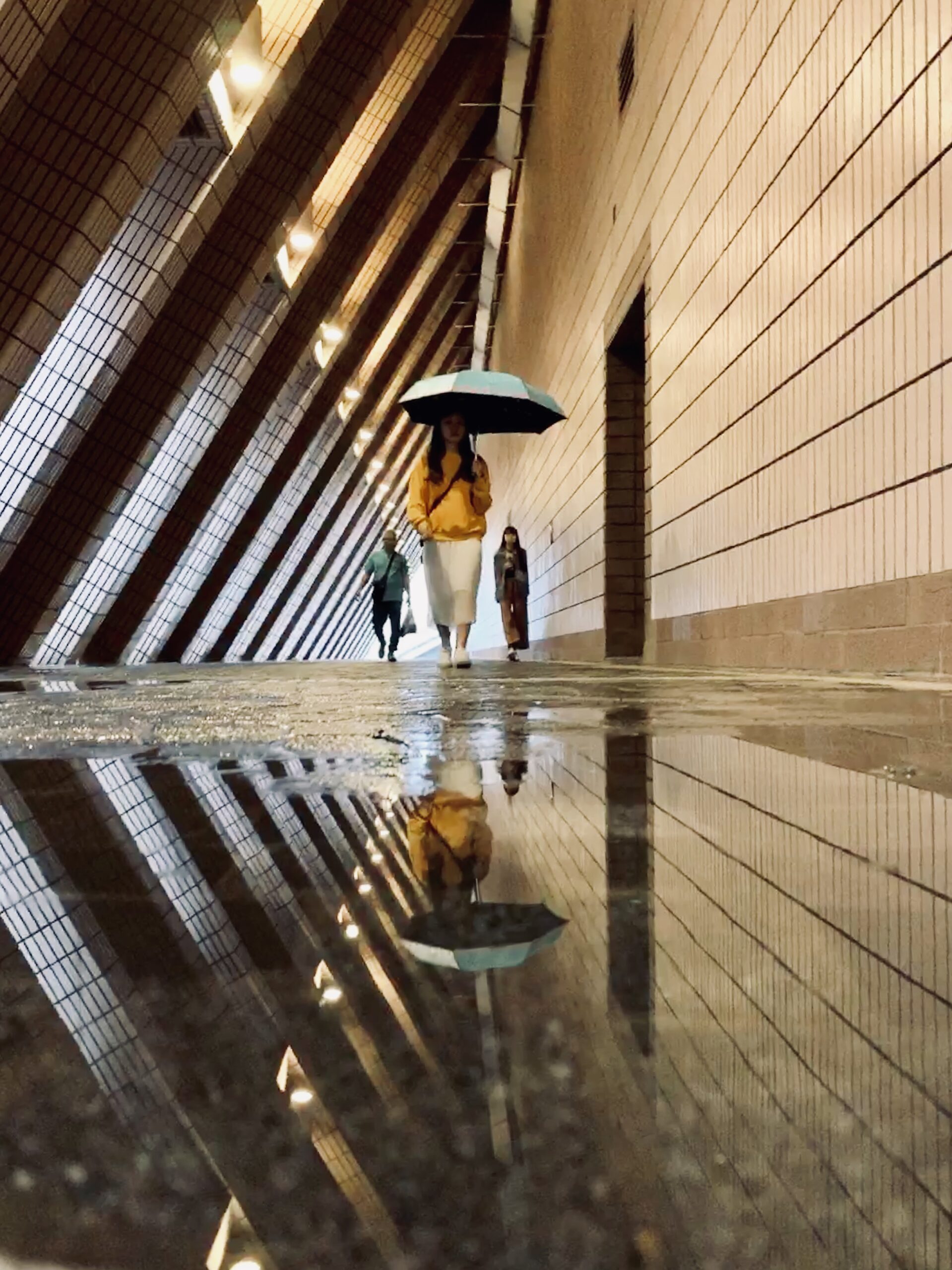 Woman walking on wet indoor floor with umbrella; Williams DeLoatche stresses documenting hazards after a premises injury.