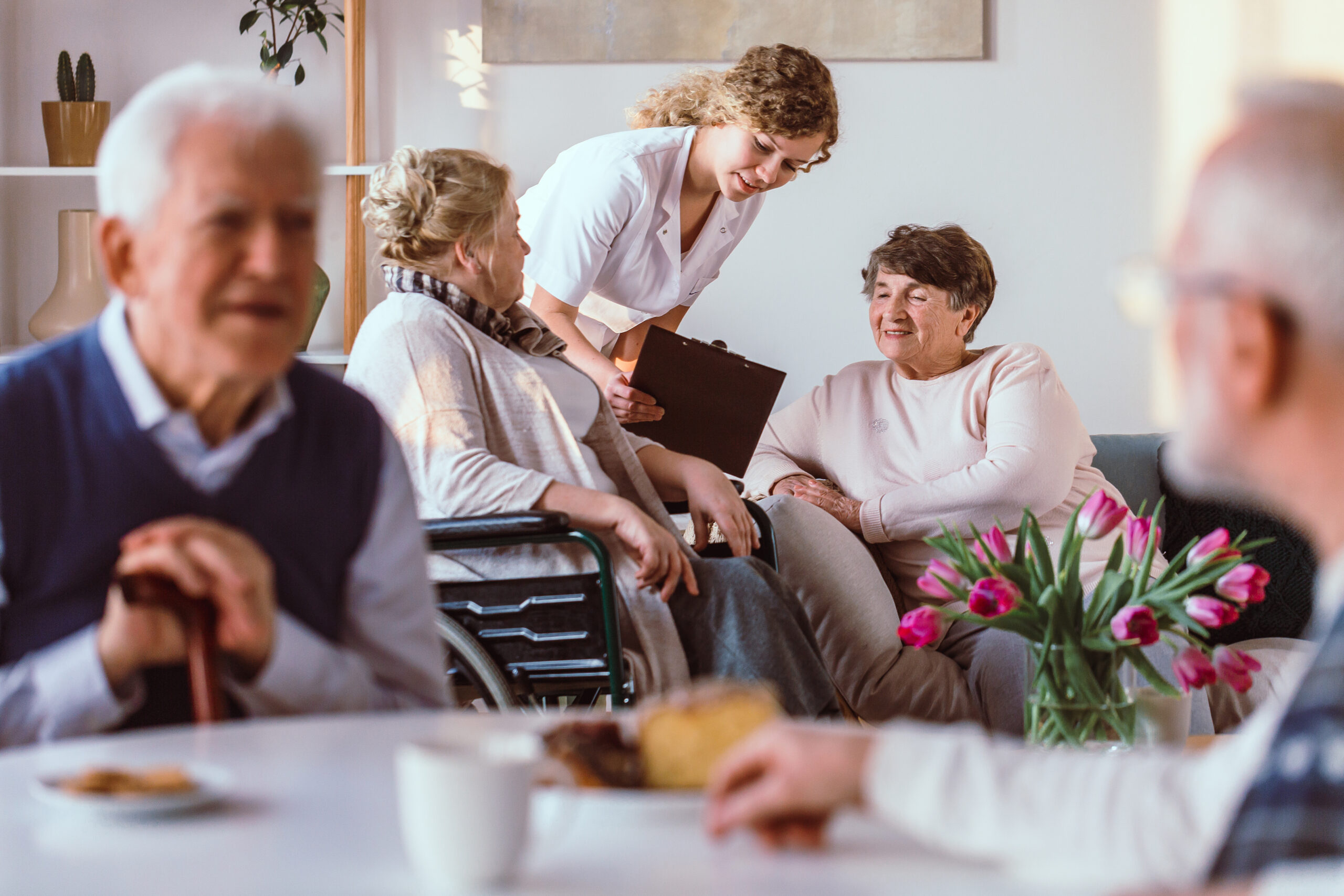 A caregiver with a clipboard engaging with elderly residents in a nursing home, fostering a warm and supportive environment. 