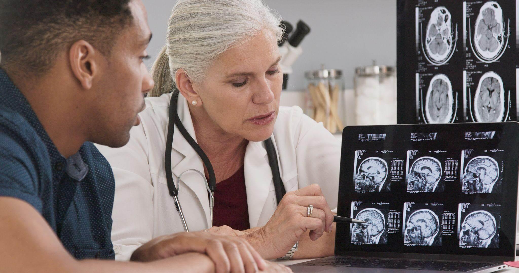 a man and a woman looking at a computer screen with brain cat scans