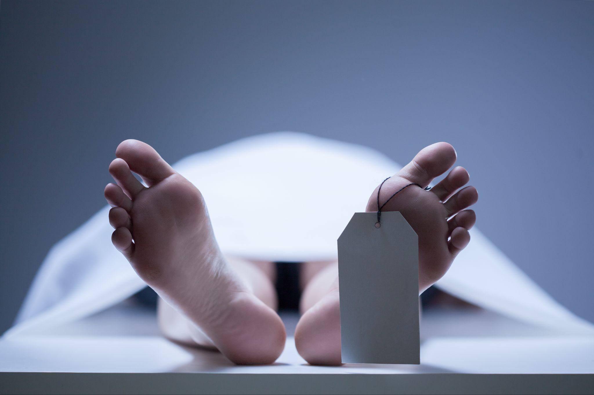 Una persona acostada en una cama con los pies apoyados en una morgue.