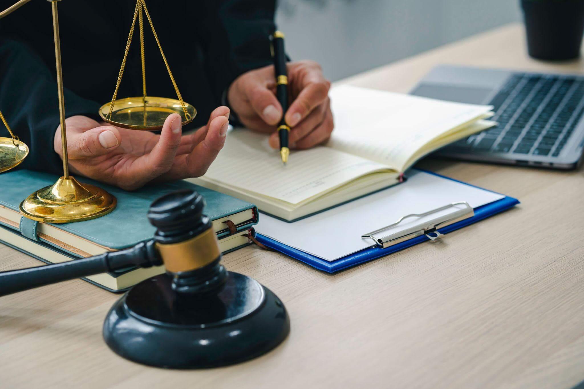 Person at desk with scale of justice and notebook