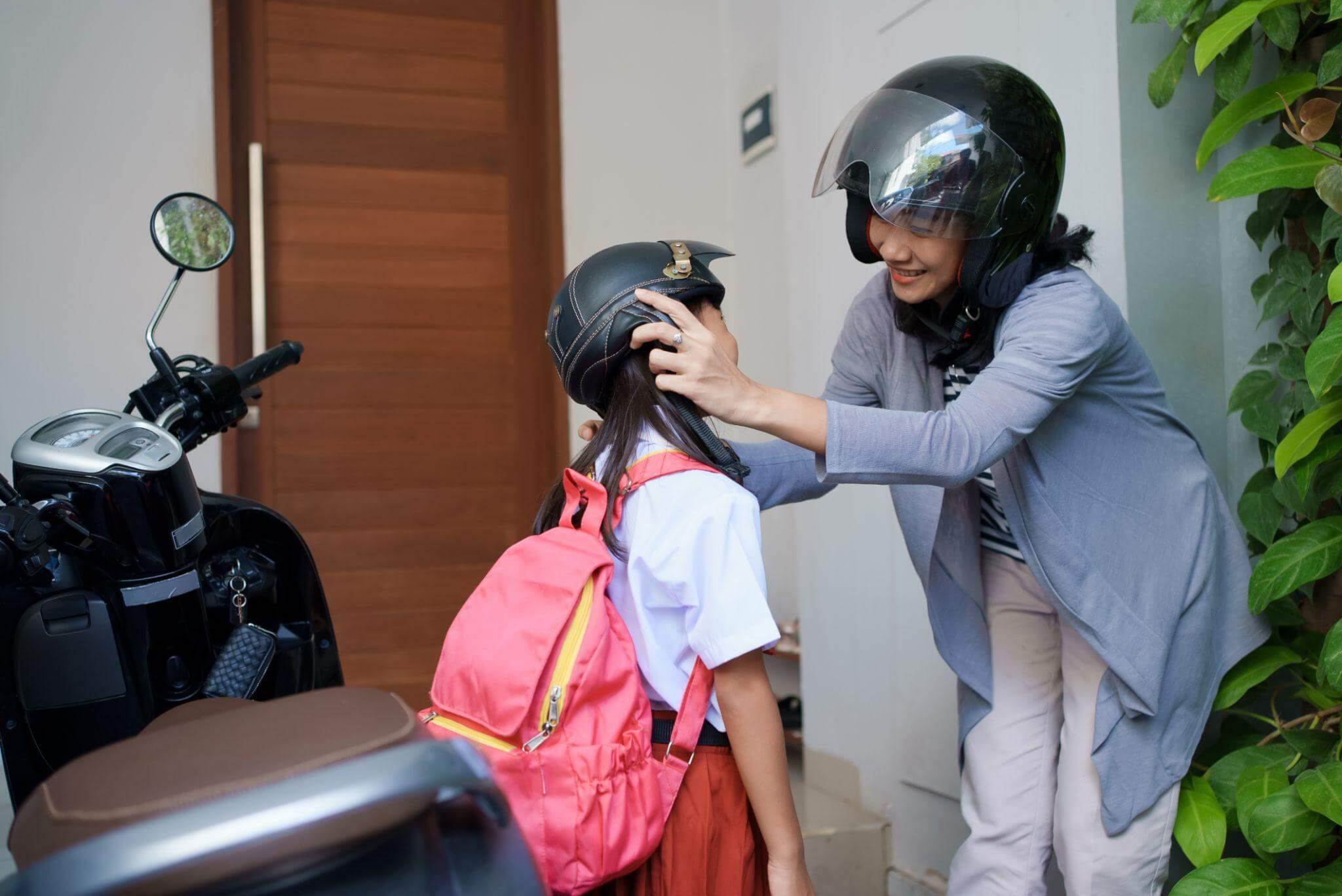 Woman helping child put on motorcycle helmet